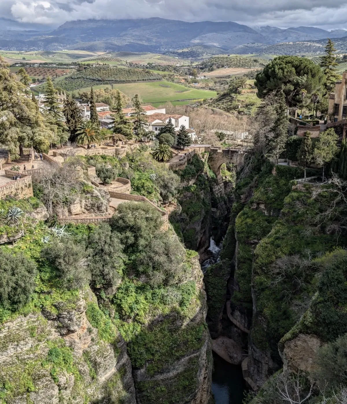 Vista aérea del Tajo de Ronda, con jardines en terrazas al borde del tajo, el río al fondo del desfiladero y el campo a lo lejos