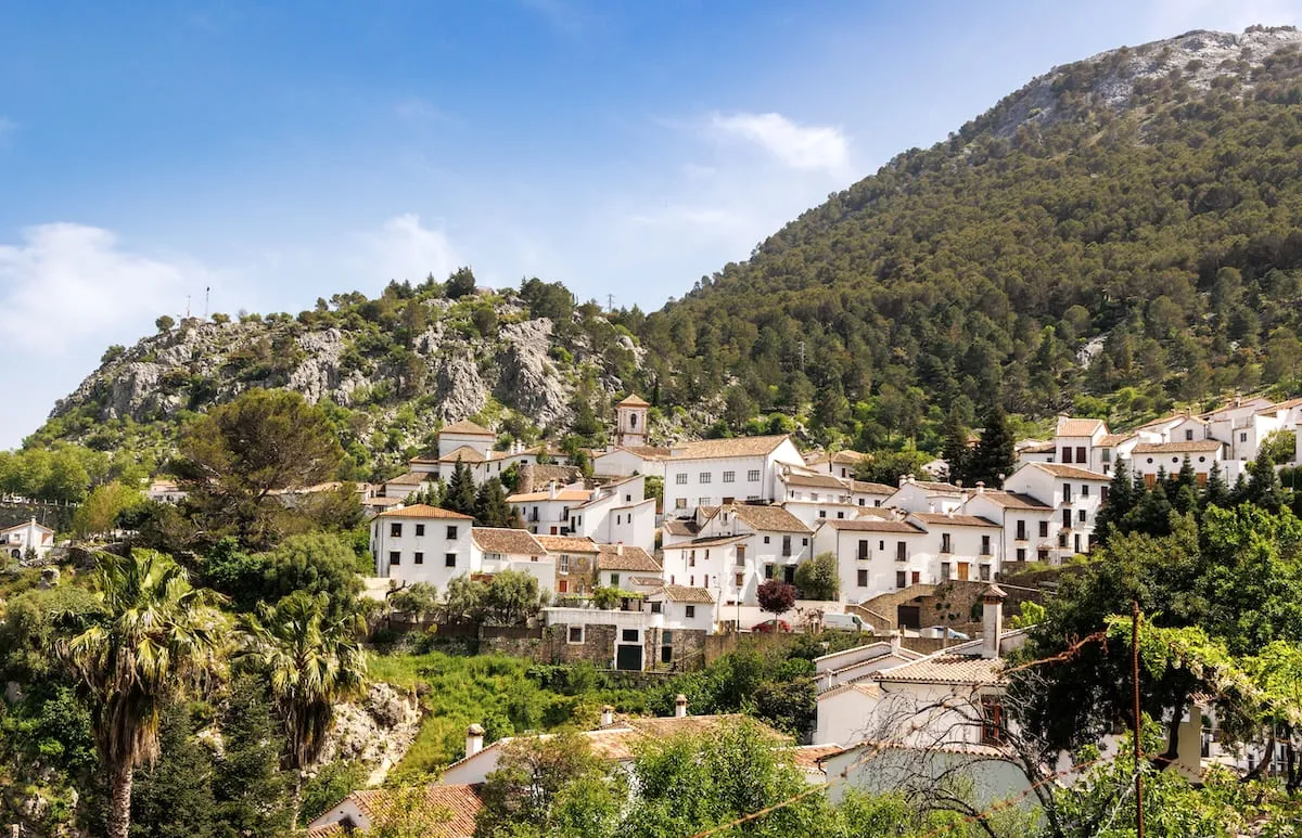 Casas blancas de Grazalema en una ladera verde bajo un pico rocoso