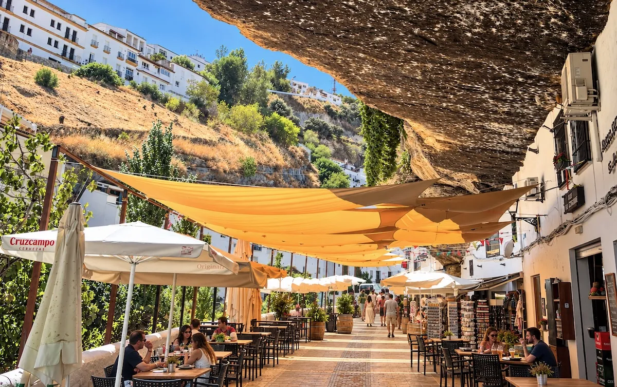Restaurant terraces with parasols and awnings under the rock overhang of a street in Setenil de las Bodegas