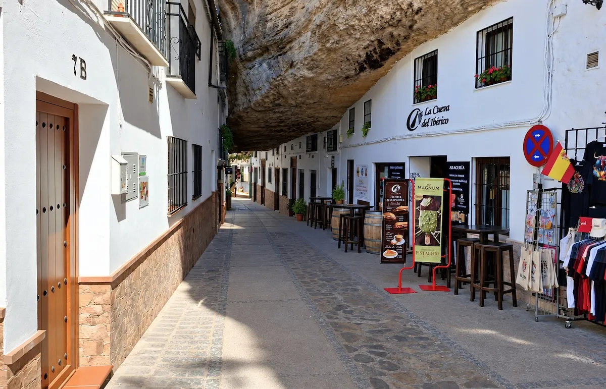Street in Setenil de las Bodegas with white houses and terraces under a huge rock overhang