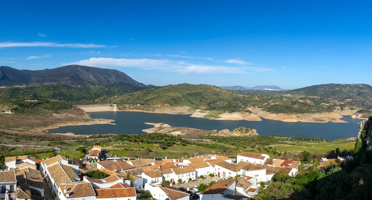 Tejados de Zahara de la Sierra sobre el embalse de Zahara-El Gastor y su presa, con las montañas de la Sierra de Grazalema
